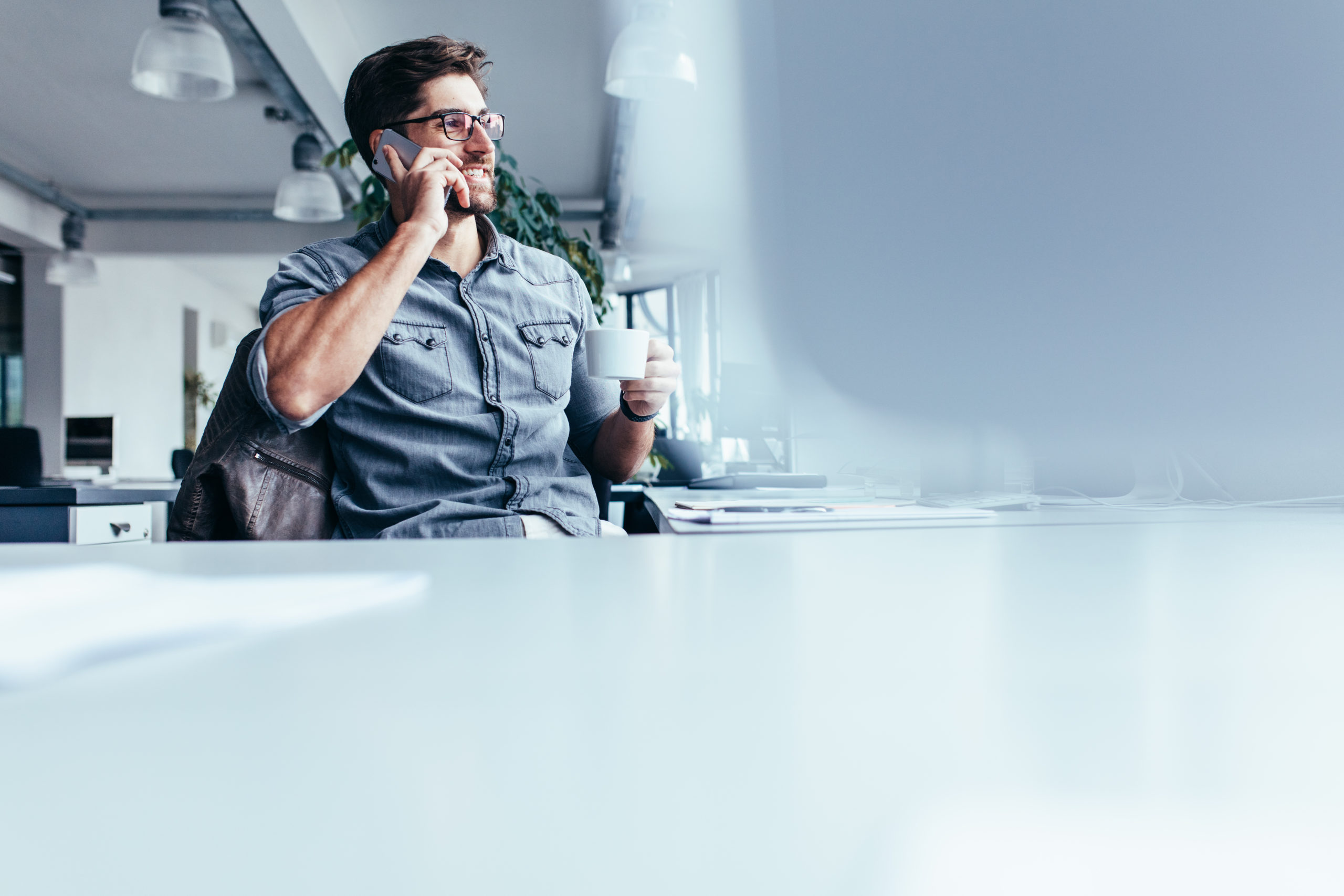 Young,Man,With,Cup,Of,Coffee,And,Talking,On,Mobile
